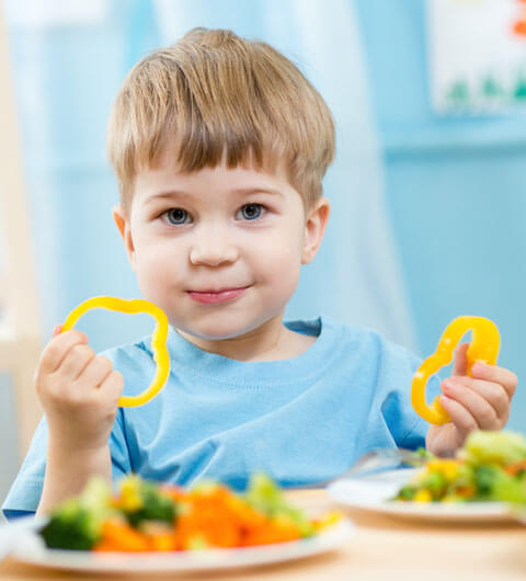 Kindergartenkind isst frisches Gemüse